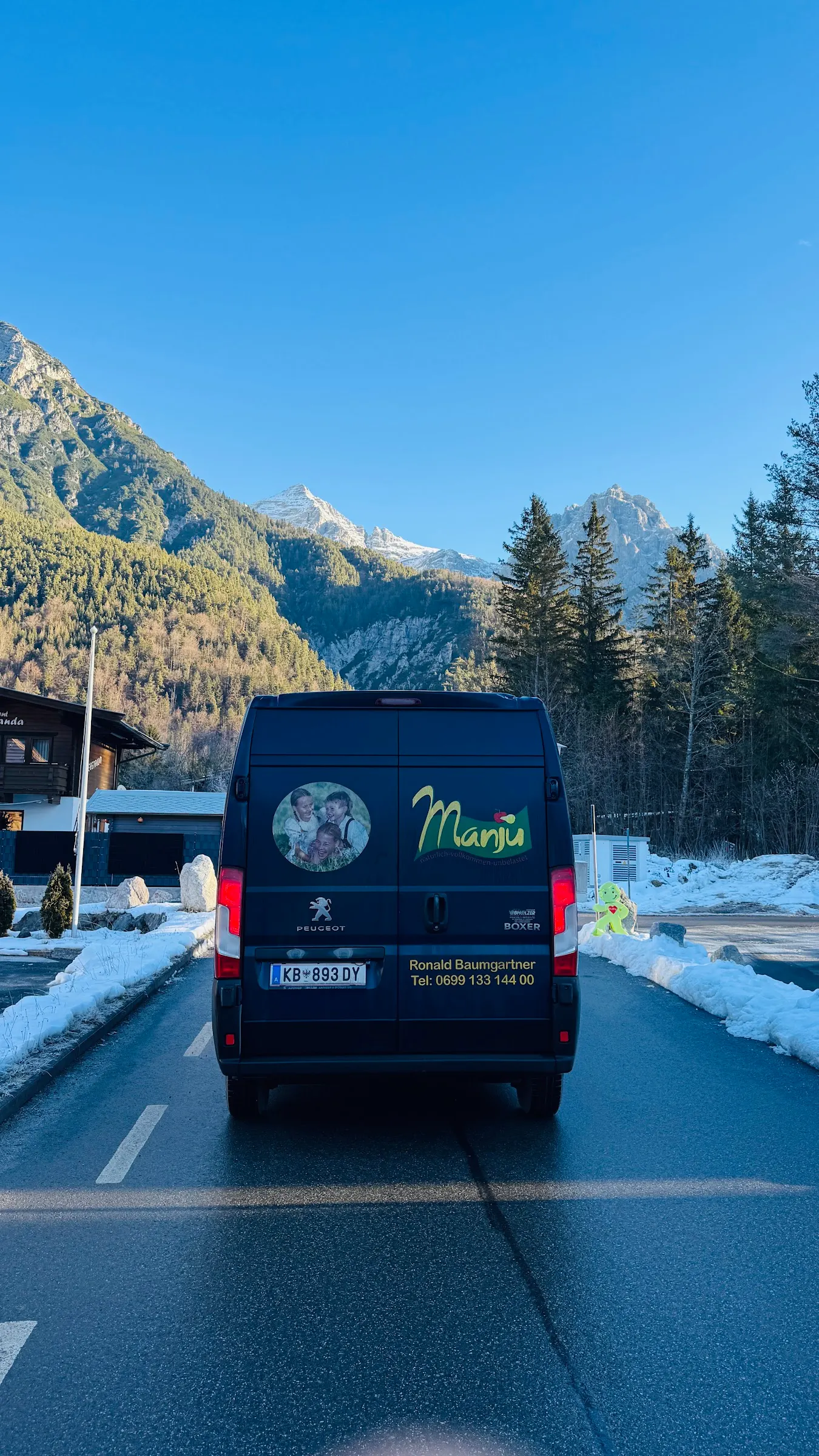 Manju-Lieferwagen auf einer verschneiten Straße vor Bergen