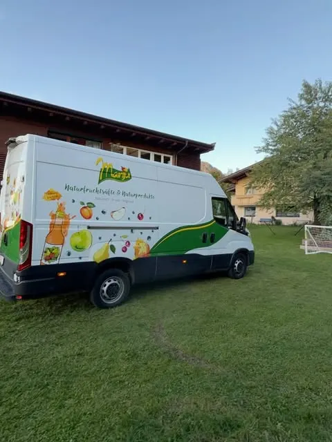 Weißer Manju-Lieferwagen mit Obstmotiven auf einer Wiese